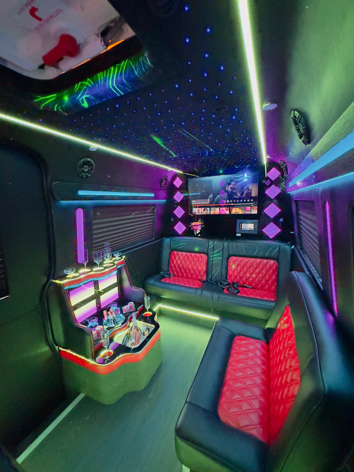 Sprinter limousine interior with LED fiber-optic star ceiling, red diamond-stitched perimeter leather, illuminated bar and 4K screen